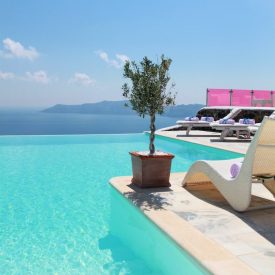 Photo by Dimitris Mourousiadis Swimming Pool near Body of Water Under Blue Sky